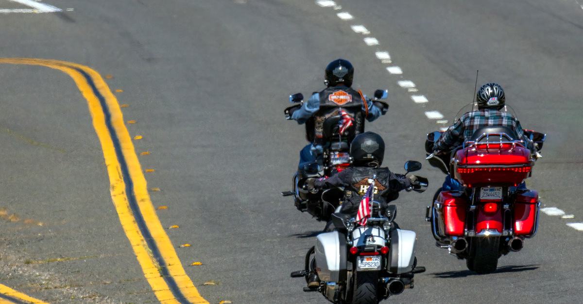 Three motorcyclists riding freely on a highway, enjoying the thrill of the open road.